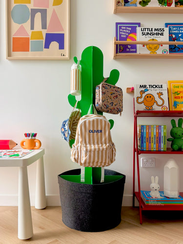 Mustard stripe mini kids backpack with personalised name “Oliver,” paired with reversible ocean friends bucket hat and construction crew mini lunch bag in a playful kids room setting