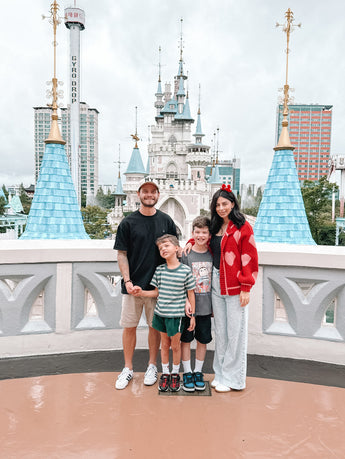 Family of four posing in front of a castle-like structure with blue towers.